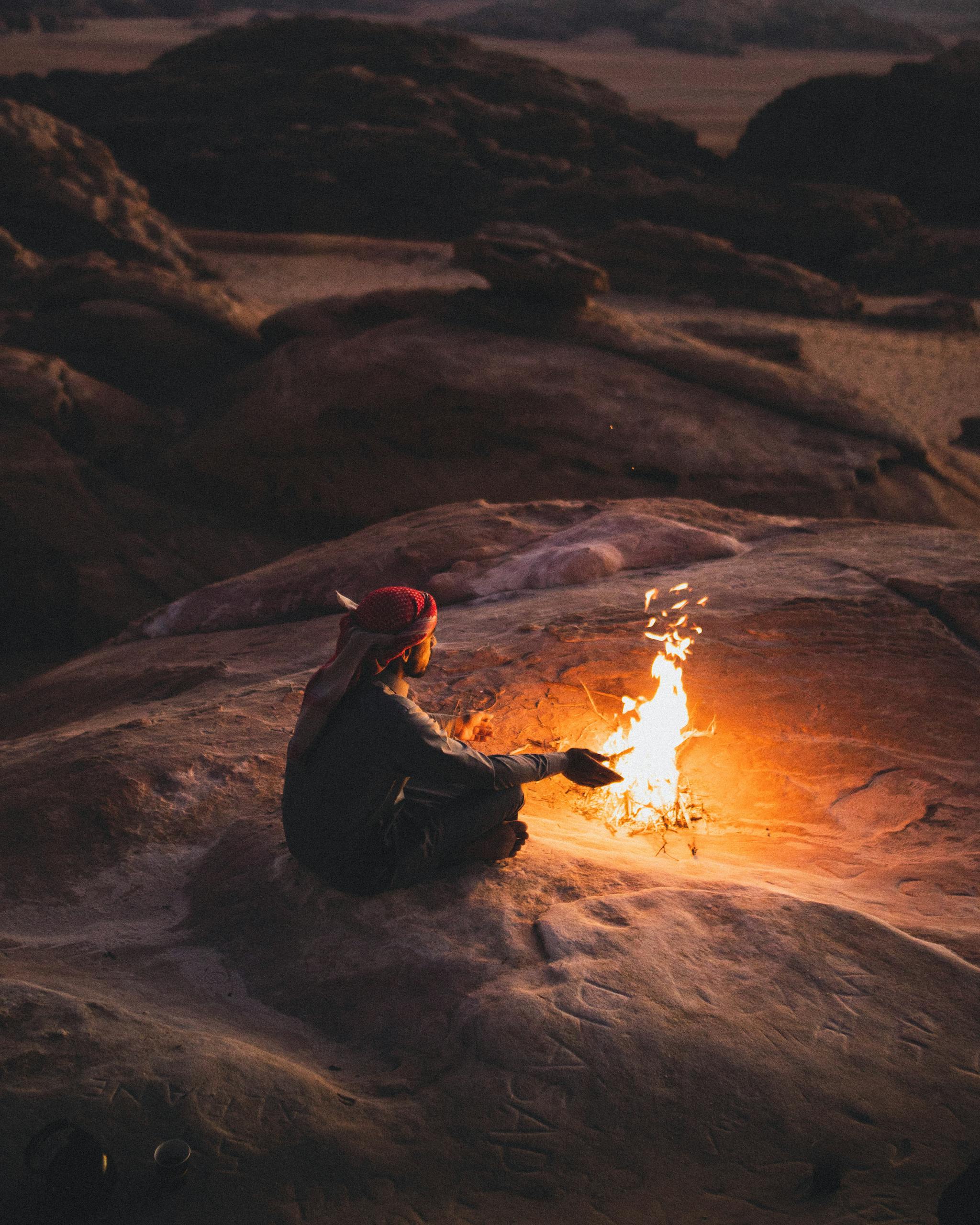 A serene scene of a man sitting by a campfire in the desert landscape of Wadi Rum, Jordan